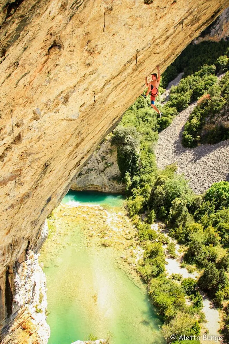 Photographie de Sébastien Bouin escaladant une montagne avec un lac en arrière-plan