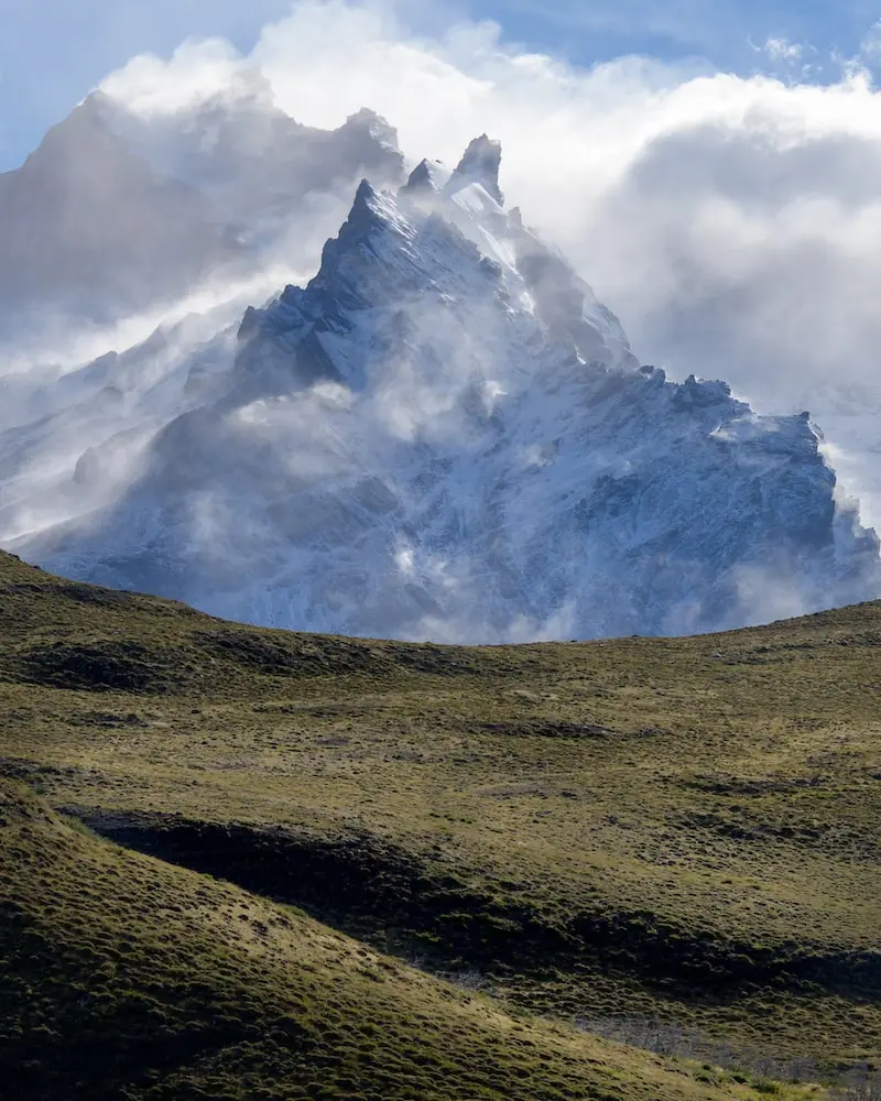 Photographie d'une prairie et d'une montagne brumeuse