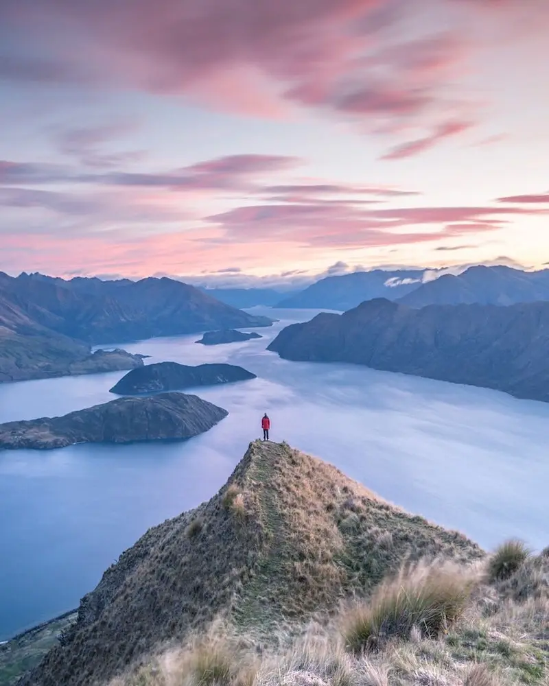 Photographie d'une personne au sommet d'une montagne sous le coucher du soleil