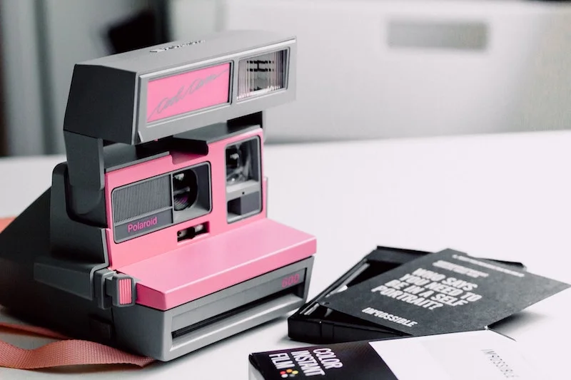 Pink and black polaroid with recharges for instant photos