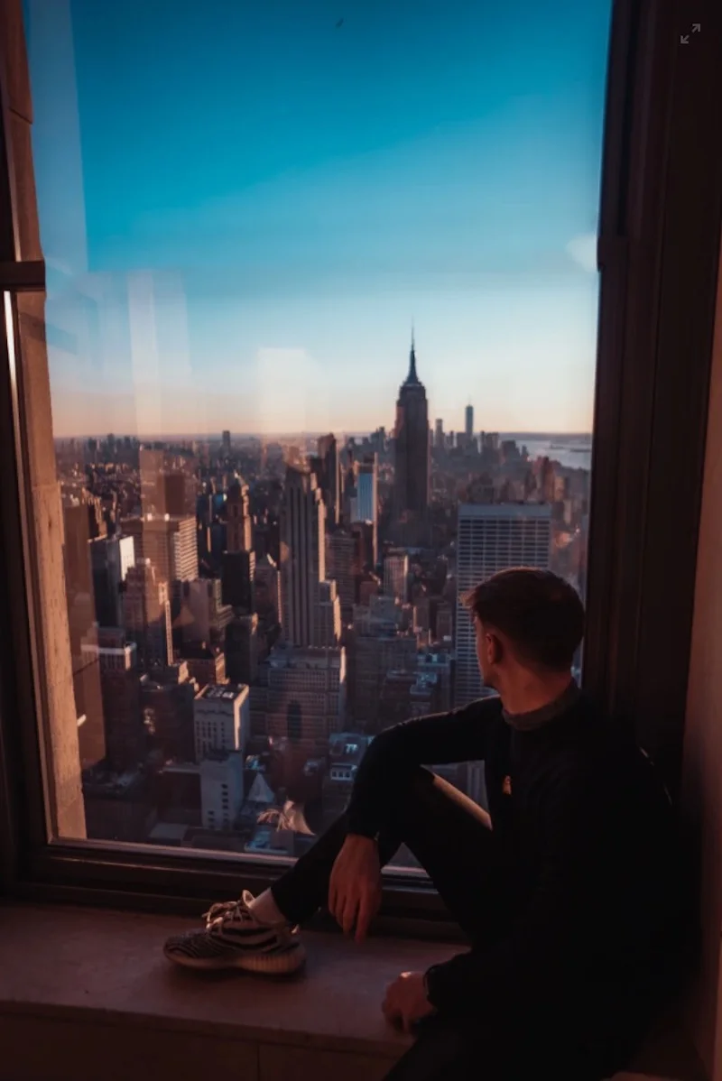 Photo instantanée unique d'un homme assis près d'une fenêtre avec vue sur la ville de New York