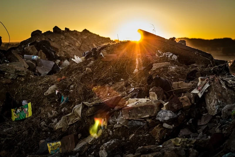 Mountains of waste with a sunset reflection in the background, affectong the climate