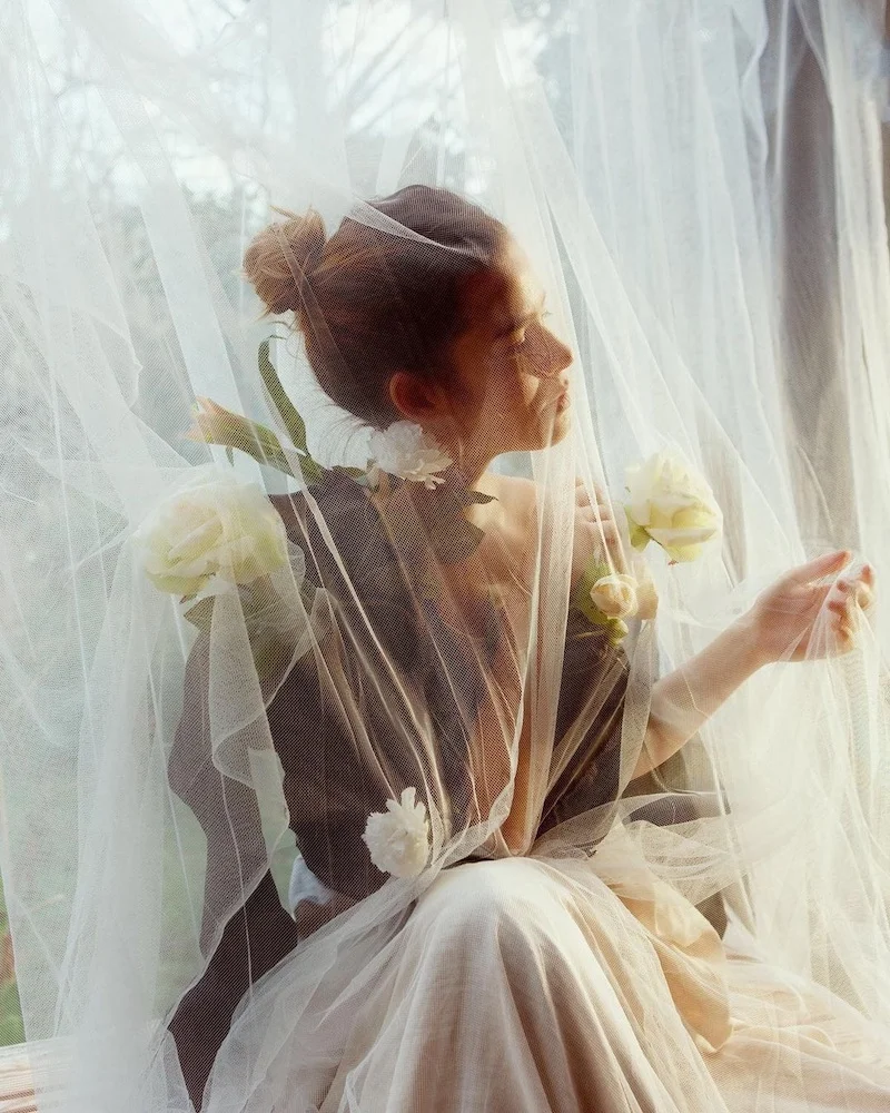 Photo d'artiste d'une jeune femme couverte d'un voile blanc avec des fleurs blanches