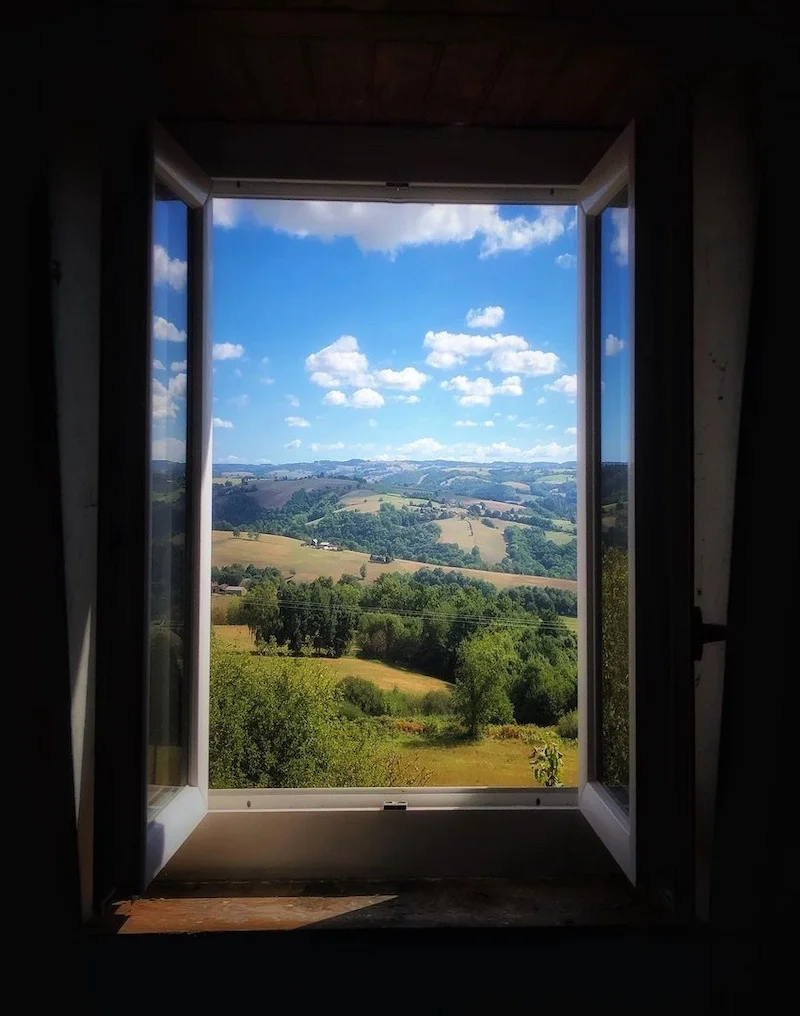 View of a sunny countryside through a dark window, #OpenWindow challenge to allow people to travel virtually during containment