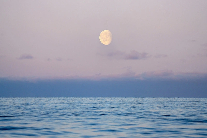 Photography of the moon on a lilac sky over the sea in the Arctic