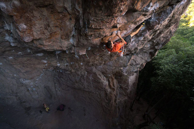 Photographie d'un homme escaladant la grotte du Blavet