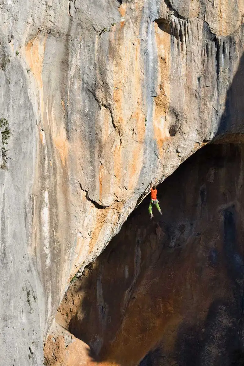 Photography of Nicolas Rousse climbing on the void of a mountain