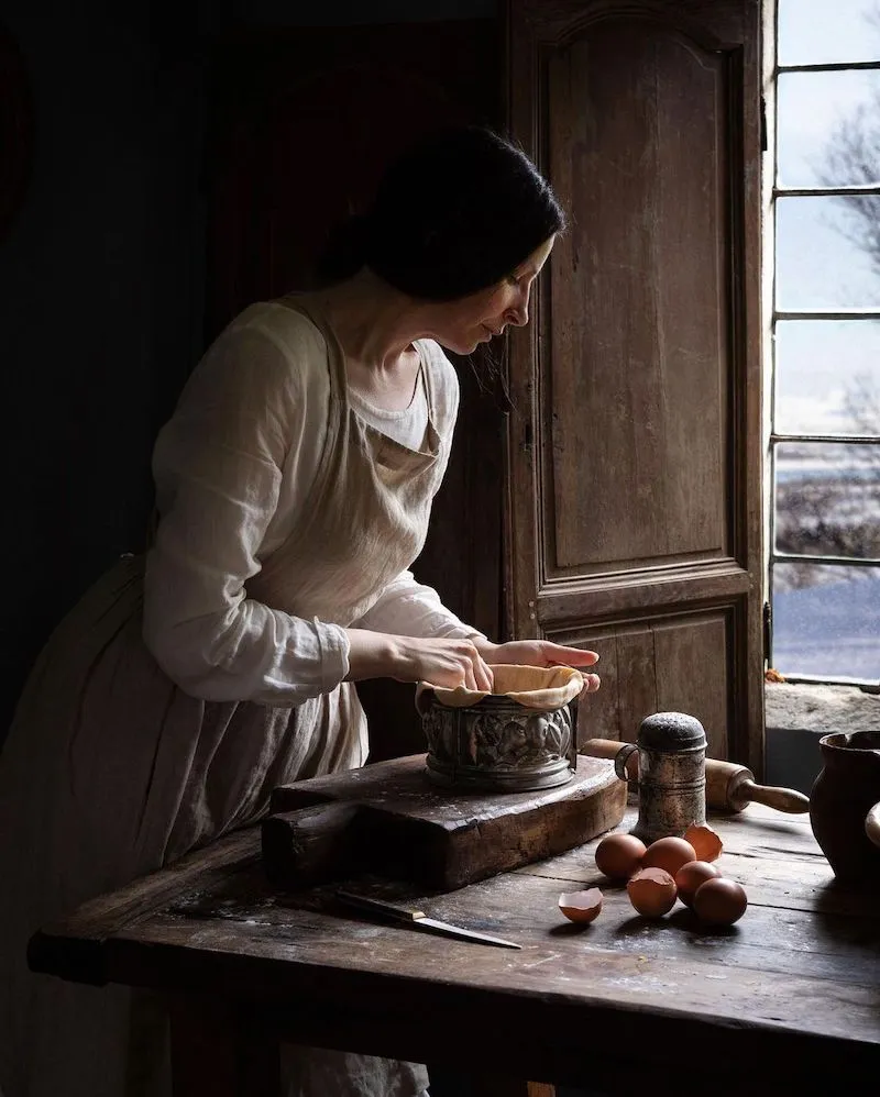 Photography of a woman putting a pastry into a mold with an open window in the background