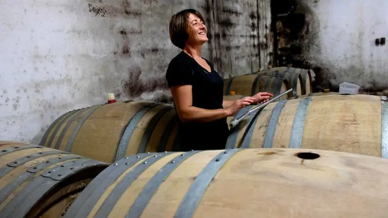 Photographie d'une femme entre des tonneaux de vin au Domaine Clavel