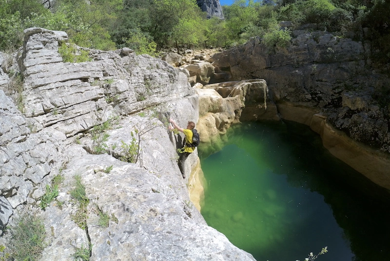 Photographie d'un homme escaladant une montagne avec un lac en arrière-plan