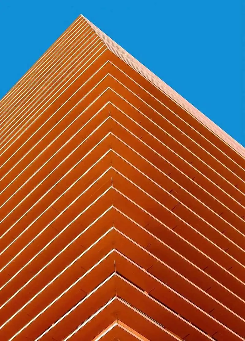 Photographie d'un bâtiment orange avec un ciel bleu derrière, prise par Ash Camas, photographe d'architecture contemporaine