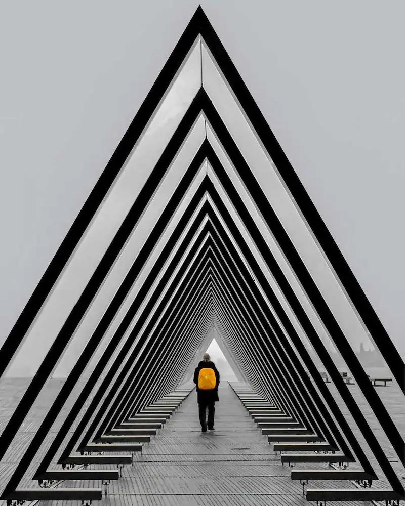 Photographie d'une structure pyramidale avec une personne marchant à l'intérieur, prise par Ash Camas, photographe d'architecture contemporaine