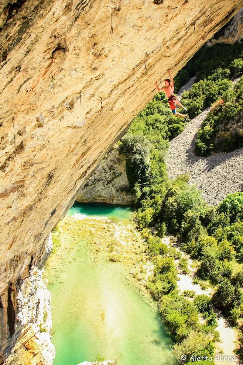 Photographie de Sébastien Bouin escaladant une montagne avec un lac en arrière-plan